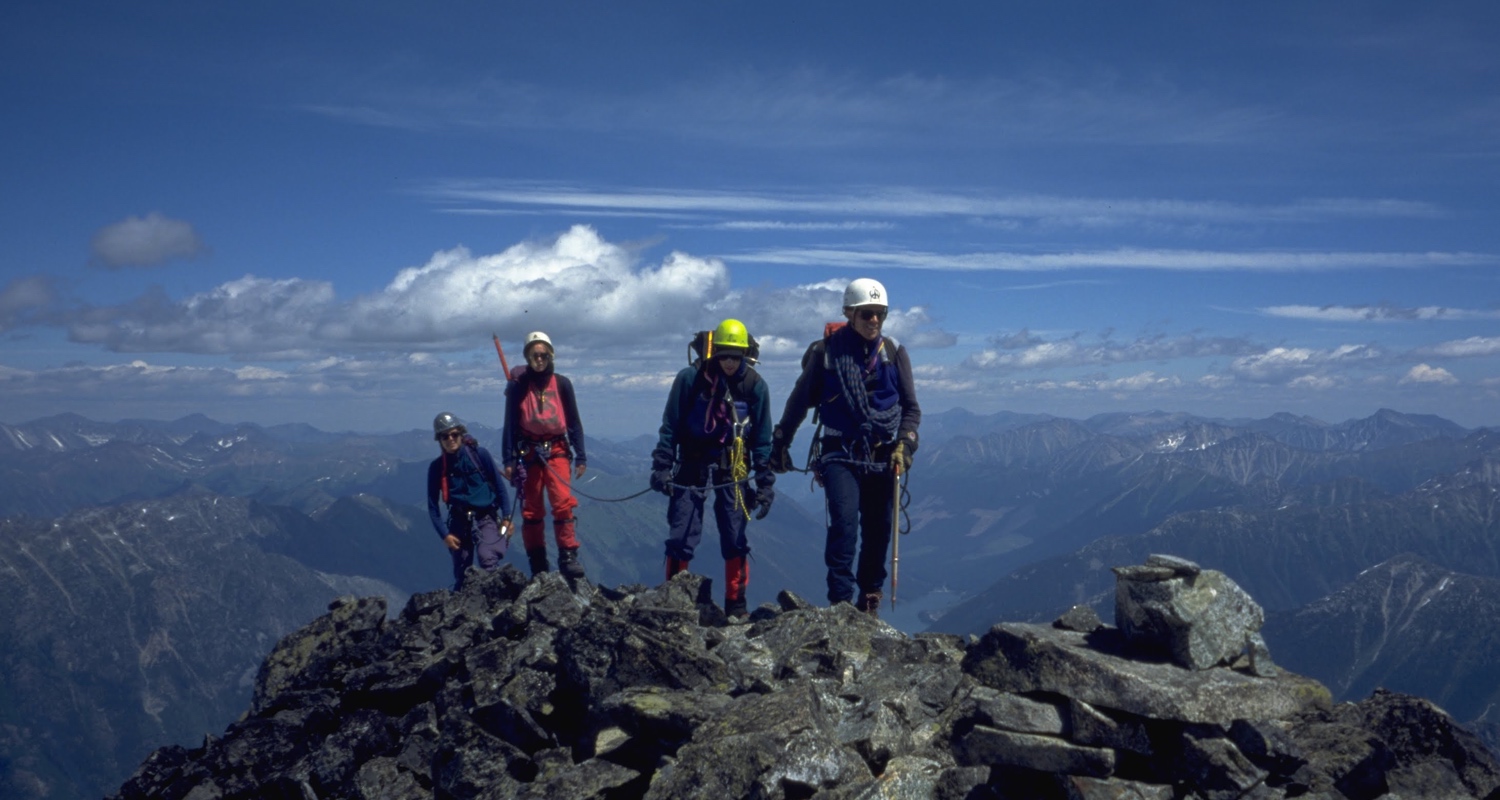 four people cabled together hiking a mountain